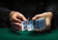 A professional dealer or croupier quickly shuffles playing cards in a club at a green table with playing chips. The concept of a Royalty Free Stock Photo