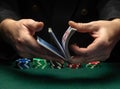 Professional dealer or croupier shuffles playing cards in a club at a green table with playing chips. The concept of a successful Royalty Free Stock Photo