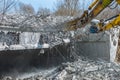 Professional demolition of reinforced concrete structures using industrial hydraulic hammer. Rods of metal fittings. Wreckage and