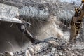 Professional demolition of reinforced concrete structures using industrial hydraulic hammer. Rods of metal fittings. Wreckage and