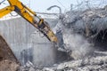 Professional demolition of reinforced concrete structures using industrial hydraulic hammer. Rods of metal fittings. Wreckage and