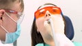Professional dentist working with patient in modern clinic, medicine concept. Media. Young patient in protective glasses
