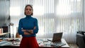 Professional designer. Portrait of a young beautiful woman in casual wear with crossed arms leaning on a table and Royalty Free Stock Photo