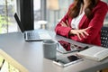 Professional and determined millennial Asian businesswoman sits at her desk with arms crossed Royalty Free Stock Photo