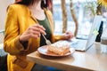 Professional digital nomad woman enjoying lemon pie while working remotely at a cafe in a yellow blazer