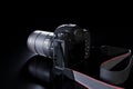 Professional digital SLR photo camera with a zoom lens and a leather strap on a black background with copy space. Top