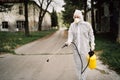 Professional disinfector in hazmat protection suit and N95 mask with chemical decontamination sprayer tank.Disinfecting streets