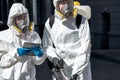 Professional disinfectors in protective hazmat suit walking through city streets