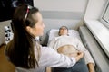 Professional doctor is examining female abdomen and kidneys using ultrasound equipment. Young caucasian woman patient is Royalty Free Stock Photo