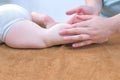 Professional doctor masseur making massage to baby on leg in clinic, closeup. Royalty Free Stock Photo