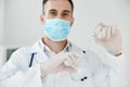 professional doctor in a medical mask holds a syringe in his hand vaccine coronavirus liquid chemistry