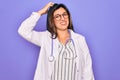 Professional doctor woman wearing stethoscope and medical coat over purple background confuse and wonder about question Royalty Free Stock Photo