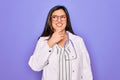 Professional doctor woman wearing stethoscope and medical coat over purple background with hand on chin thinking about question, Royalty Free Stock Photo