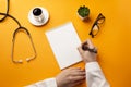 Professional doctor writing medical records in a notebook with stethoscope, coffee cup and glasses Royalty Free Stock Photo