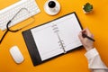 Professional doctor writing medical records in a notebook with stethoscope, keyboard, coffee cup and mouse Royalty Free Stock Photo