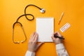 Professional doctor writing medical records in a notebook with stethoscope, syringe and pills Royalty Free Stock Photo