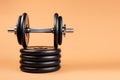 Professional dumbbell and weight plates over beige background. Black metal dumbbell with chrome silver handle. Gym Royalty Free Stock Photo