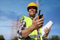 Electrician near high voltage tower, focus on hand with portable radio station