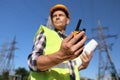 Electrician near high voltage tower, focus on hand with portable radio station