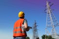 Electrician with papers near high voltage tower