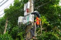 A professional electrician performs installation work on a pole. An electrician in professional equipment, working in dangerous