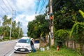 A professional electrician performs installation work on a pole. An electrician in professional equipment, working in dangerous