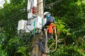 A professional electrician performs installation work on a pole. An electrician in professional equipment, working in dangerous