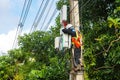 A professional electrician performs installation work on a pole. An electrician in professional equipment, working in dangerous