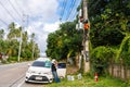 A professional electrician performs installation work on a pole. An electrician in professional equipment, working in dangerous