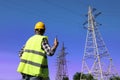 Electrician with portable radio station near high voltage tower