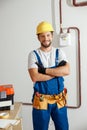 Professional electrician technician in uniform, hard hat and protective gloves smiling at camera while standing with Royalty Free Stock Photo