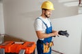 Professional electrician technician in uniform and hard hat putting on protective gloves while standing indoors Royalty Free Stock Photo