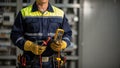 Professional electrician in uniform and hard hat using a digital multimeter to test an electrical control panel Royalty Free Stock Photo