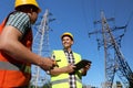 Electricians in uniforms near high voltage towers