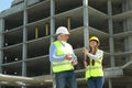 Professional engineer and foreman with tablet in safety equipment at construction site Royalty Free Stock Photo