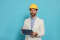 Professional engineer in hard hat with clipboard on light blue background Royalty Free Stock Photo