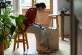 Professional enthusiastic woman artificer works sits near potters wheel making jugs from clay