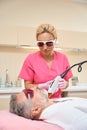 Professional experienced cosmetologist doing laser hair removal to man