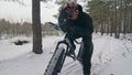 Professional extreme sportsman biker riding fat bike in outdoors. Cyclist ride in winter in snow field, forest. Man does