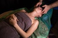 Professional facial massage. Male masseur makes procedures on a female face on a dark background Royalty Free Stock Photo