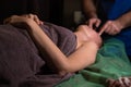 Professional facial massage. Male masseur makes procedures on a female face on a dark background Royalty Free Stock Photo