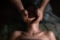 Professional facial massage. Male masseur makes procedures on a female face on a dark background Royalty Free Stock Photo