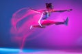 Professional female athlete, runner training isolated on blue studio background in mixed pink neon light. Healthy