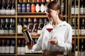 Pretty female bartender rates red wine, looks at its color, evaluates the density and tartness of an alcoholic drink