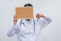 Professional female doctor in white coat over white isolated background and white blank board and Thumbs down. Concept of Royalty Free Stock Photo