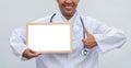 Professional female doctor in white coat over white isolated background with white blank board and Thumbs up and smile. Concept of Royalty Free Stock Photo