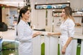 Professional female doctor and young nurse talking, standing in clinic lobby. Physicians colleagues working together Royalty Free Stock Photo