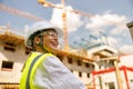 Smiling female construction worker in protective helmet standing against on construction background Royalty Free Stock Photo