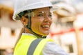 Smiling female construction worker in protective helmet standing against on construction background Royalty Free Stock Photo