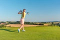 Professional female golf player smiling while swinging a driver club Royalty Free Stock Photo